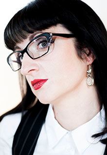 Business-Portrait einer Frau mit Brille und rotem Lippenstift im Profil