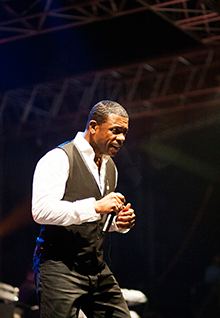 Sänger im dunklen Anzug performt mit Mikrofon auf der Bühne