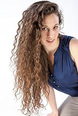 Portrait einer Frau mit langen lockigen Haaren in dunkelblauem Top